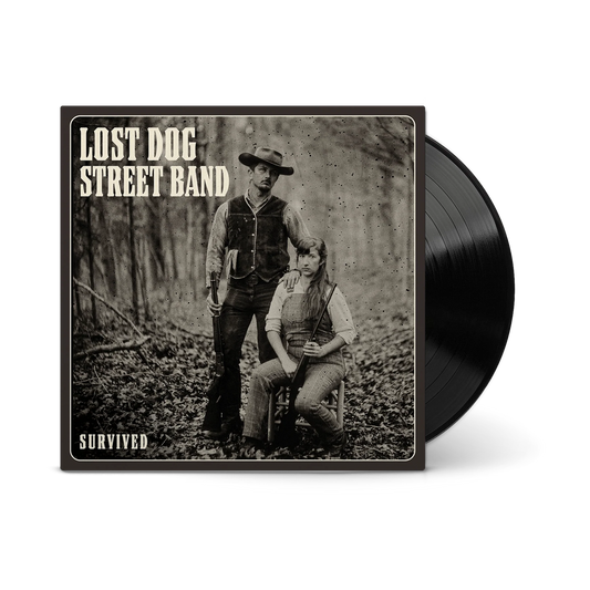 A vinyl record partially pulled from its square album cover. The cover features a sepia-toned photograph of 'LOST DOG STREET BAND' with the text 'SURVIVED'.
