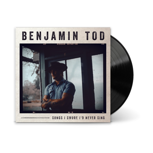 A vinyl record partially pulled from its album cover. The cover reads 'BENJAMIN TOD' and 'SONGS I SWORE I'D NEVER SING,' with a photo of a man in a cowboy hat by a window.